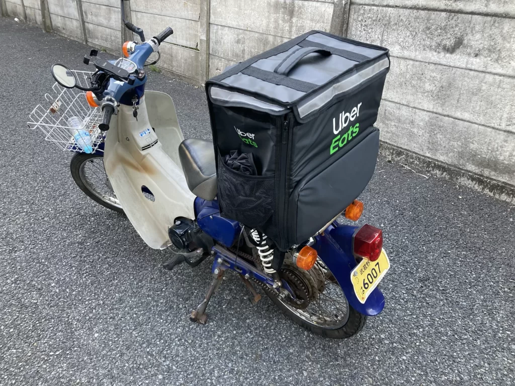 Uber Eatsの配達バッグを積んだスーパーカブが路地に停車している様子